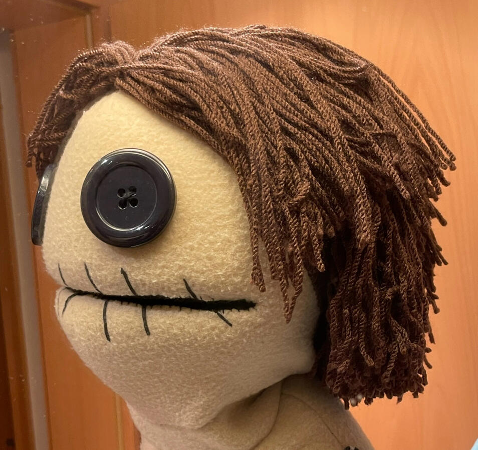 Wool wig made by sewing knitting wool with sewing machine and stitching sewn sections to the fabric head