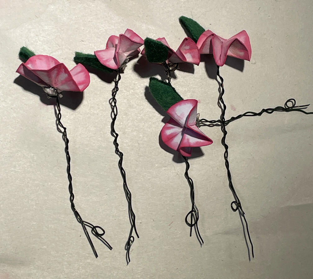 Cherry blossoms made from dyed paper and cut green felt fabric glued to twisted thin wire